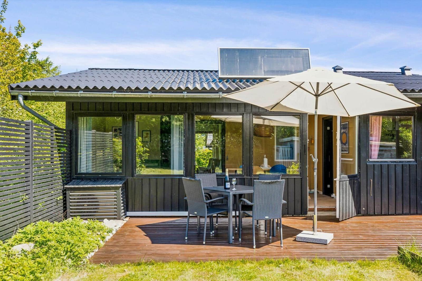 House with terrace, table, chairs, and umbrella. Solar panel on roof.