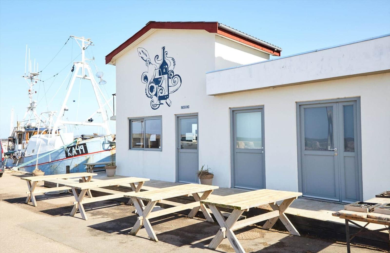 Apartment with outdoor area, wooden tables, and view of boat.