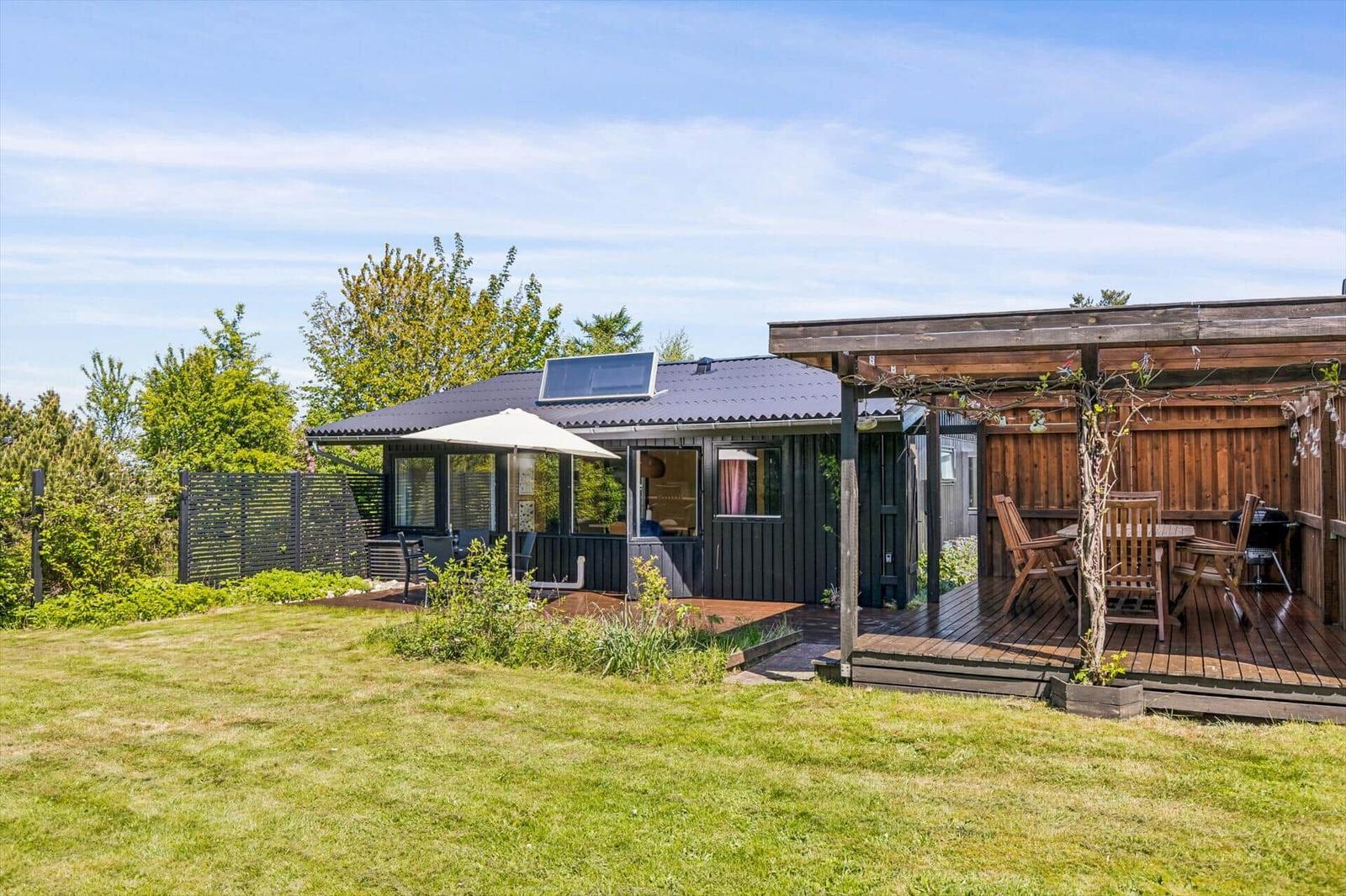 House with terrace, grill and parasol in the garden.