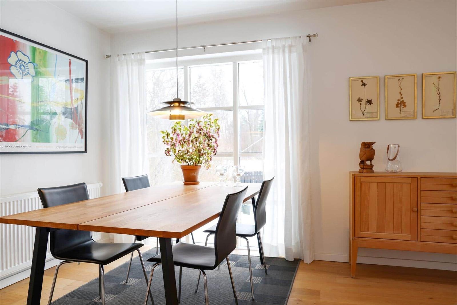 Dining room with wooden table, black chairs, window, and sideboard.