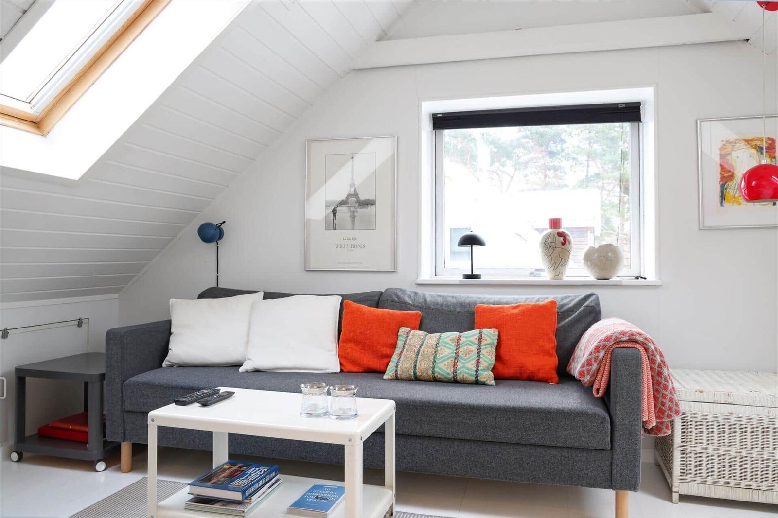A living room with a gray sofa, orange cushions, and a white coffee table.