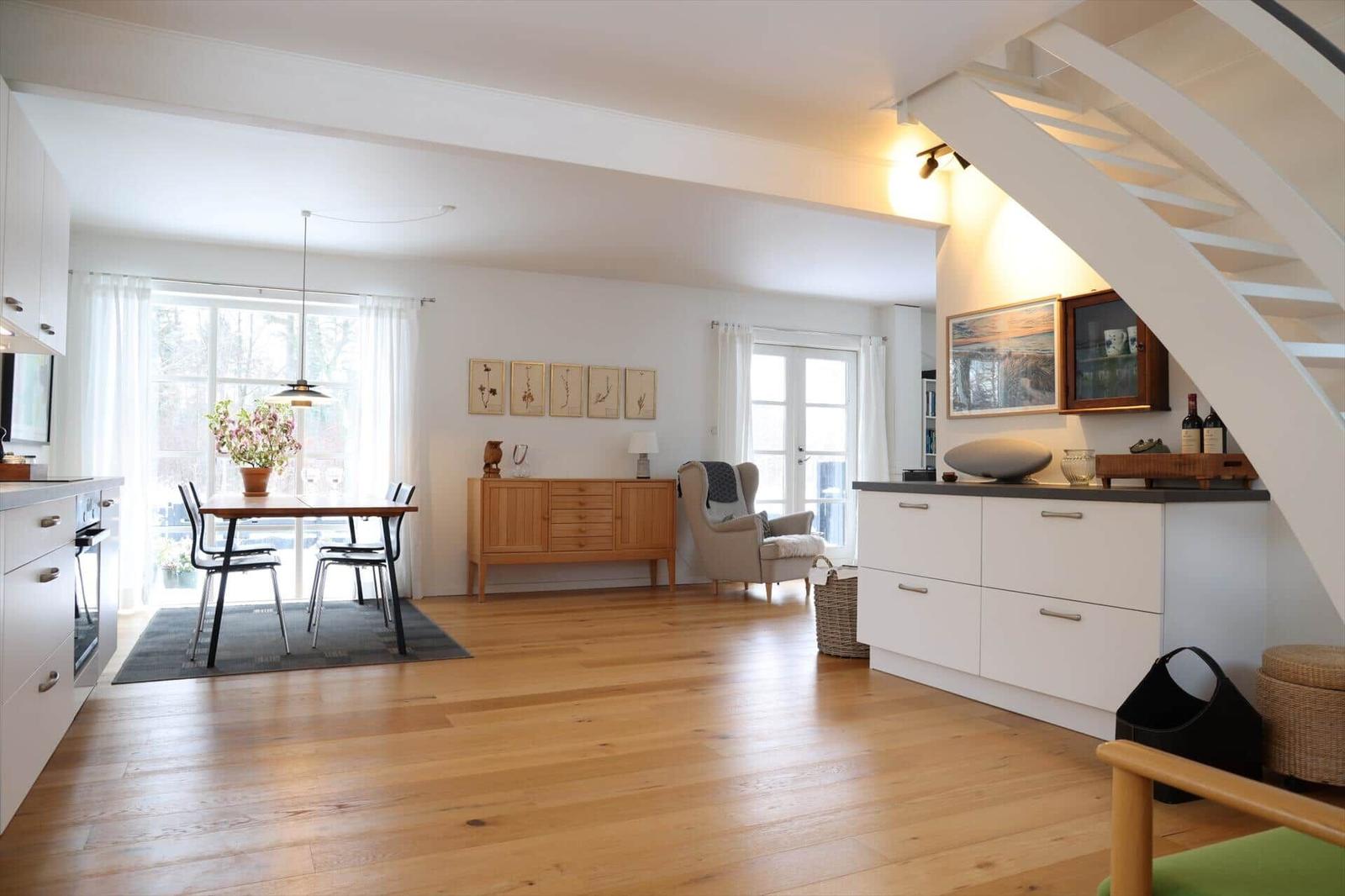 Living and dining area with hardwood floor, dining table, and staircase to upper level.