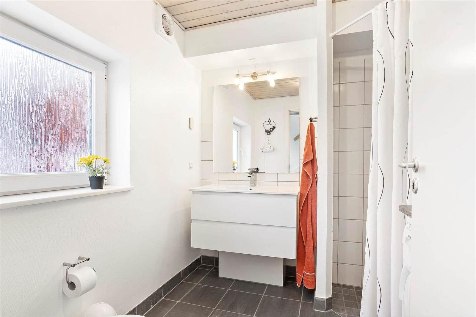 Bathroom with sink, shower, and window with flowers.