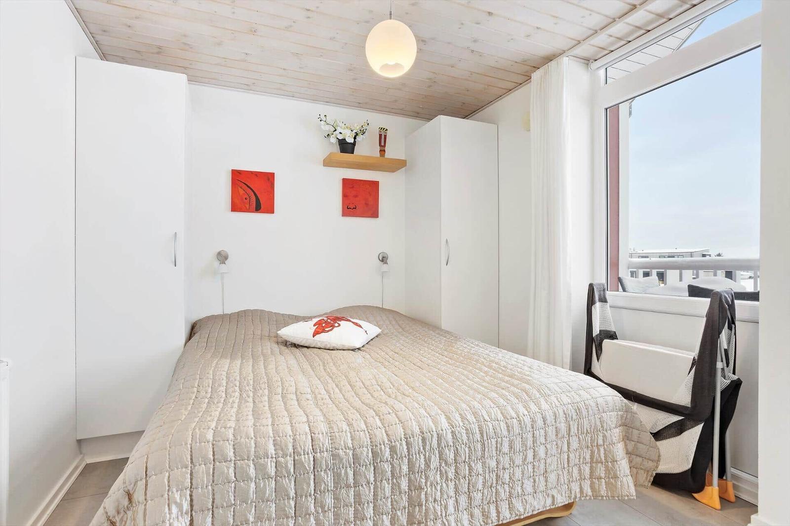 Bedroom with bed, white closets, and large window with view.
