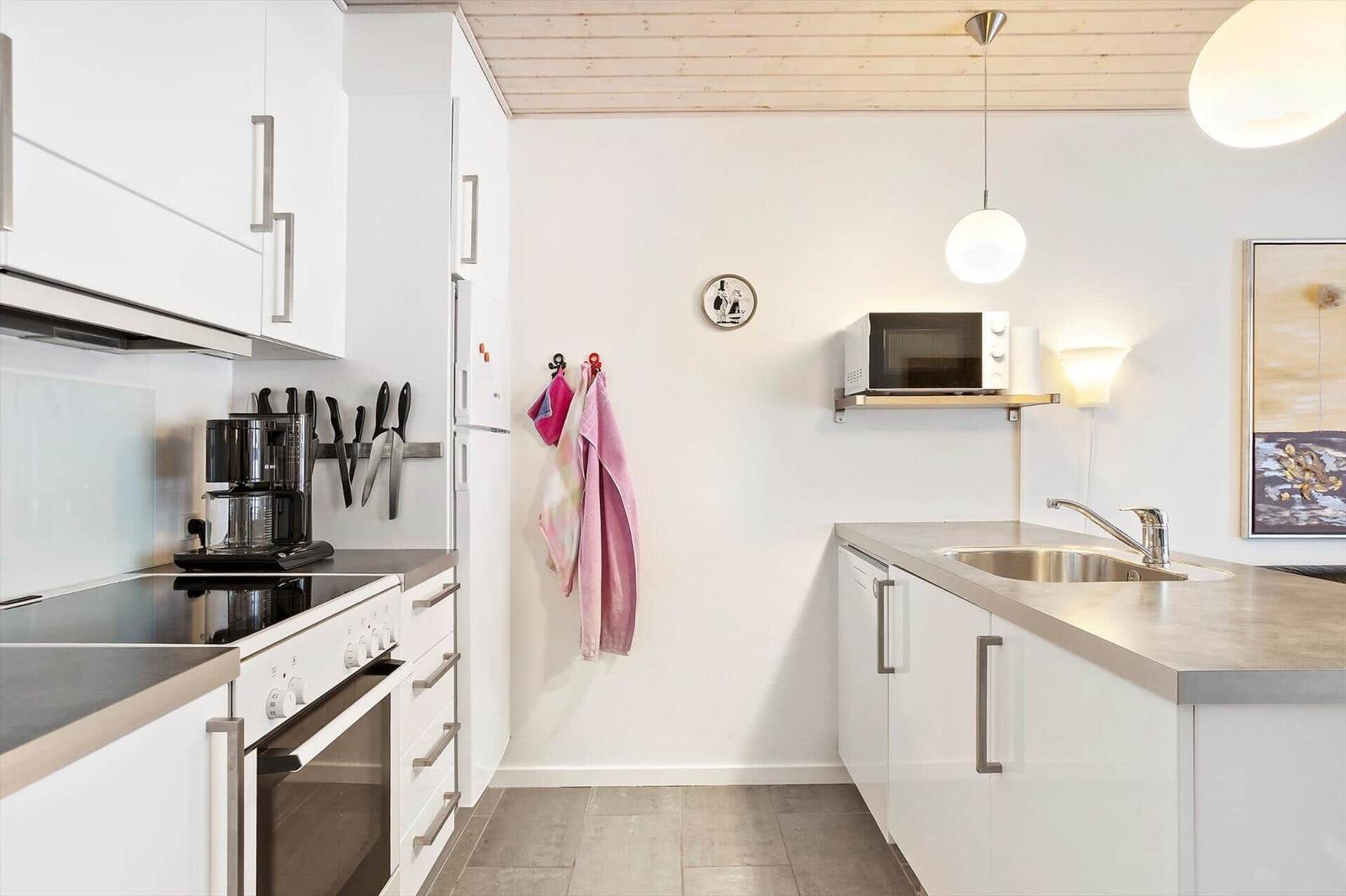 Kitchen with white cabinets, stainless steel sink, and microwave mounted on wall.