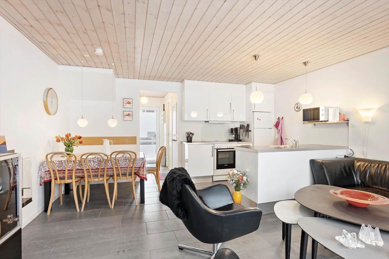 Open space with kitchen, dining area, and seating. Wooden ceiling and modern furnishings.