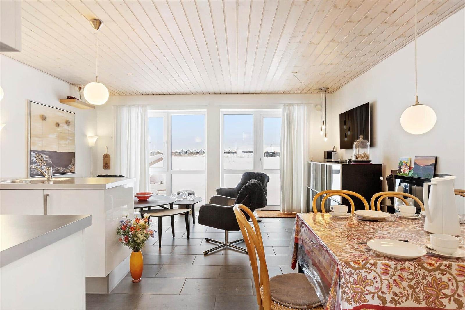 Kitchen and dining area with large windows and wooden ceiling.