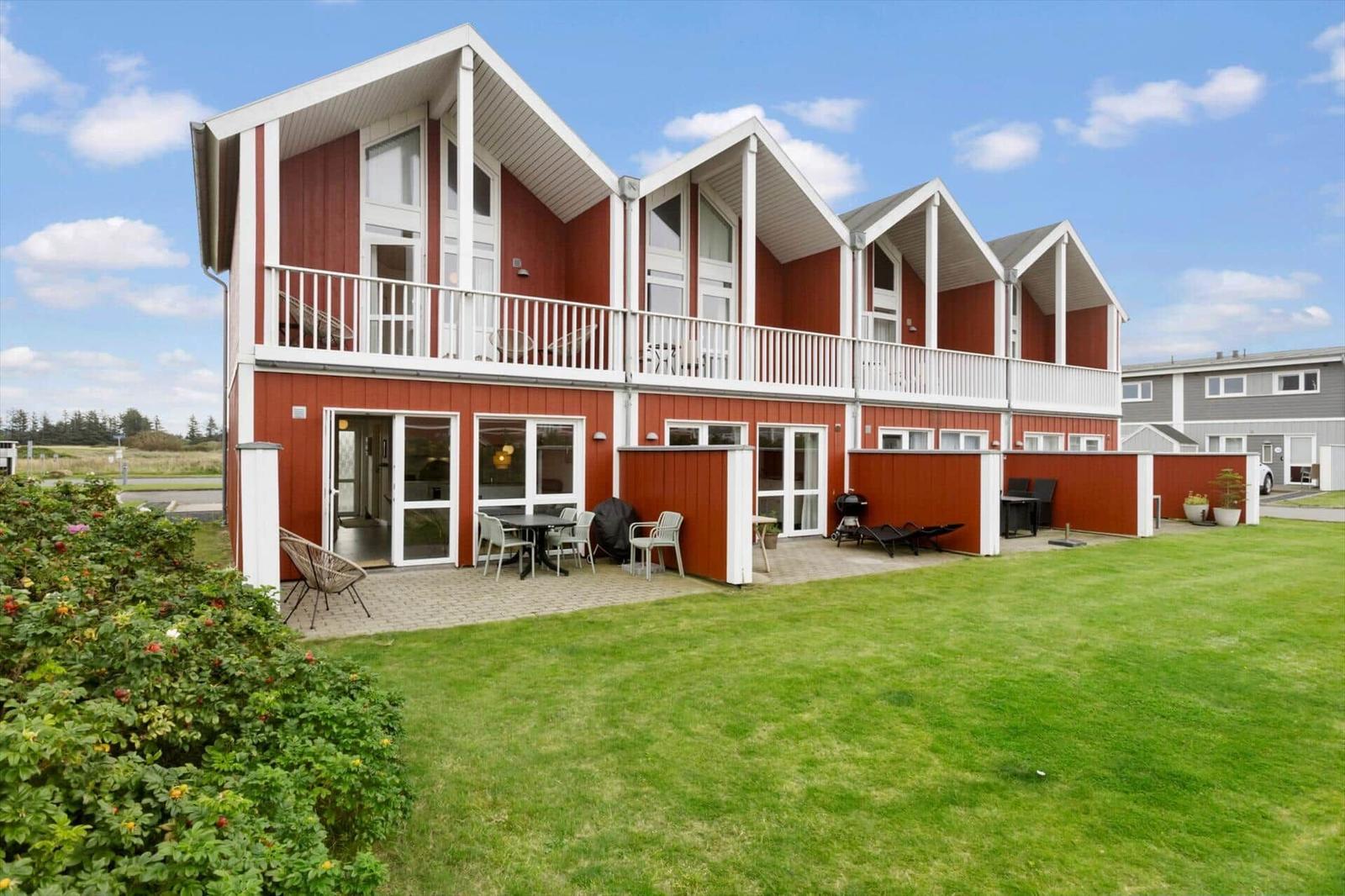 Red vacation house with balcony and garden. Outdoor terrace with seating.