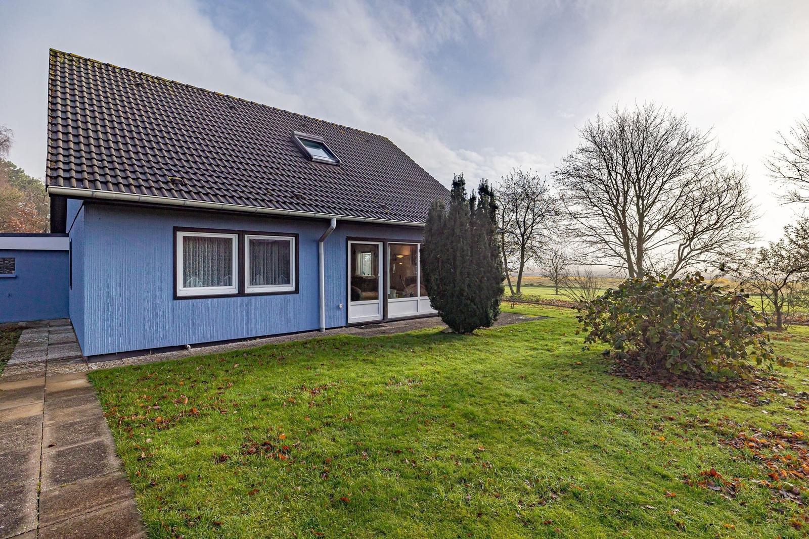 Blau gestrichenes Haus mit Dachfenster und Garten. Durchgehendes Fenster und Tür.