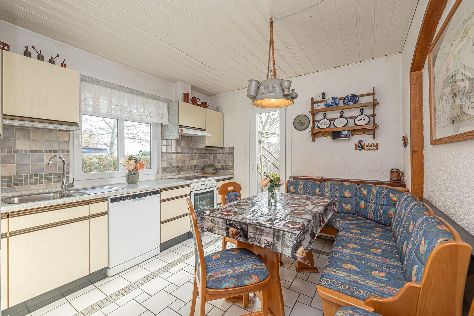 Küche mit Essbereich, Holzmöbel und gemusterten Sitzkissen.