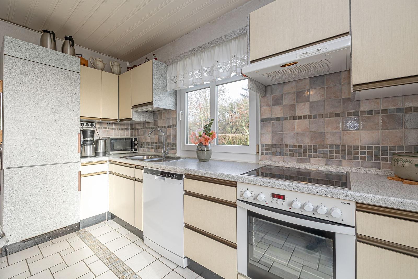 Küche mit Arbeitsplatte, Herd, Spüle und Fenster.