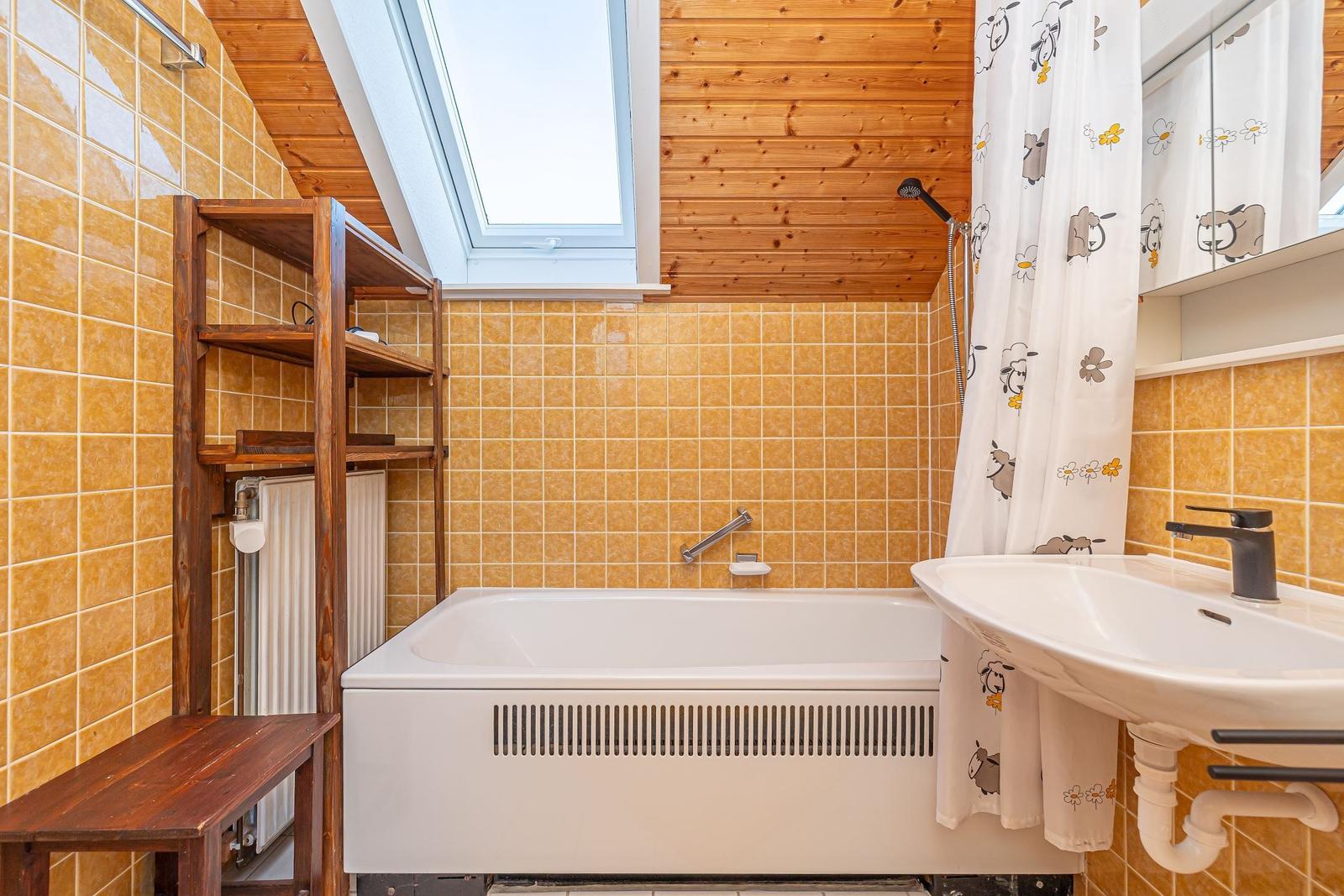 Bad mit Badewanne, Duschkabine und Waschbecken unter Dachschrägen.