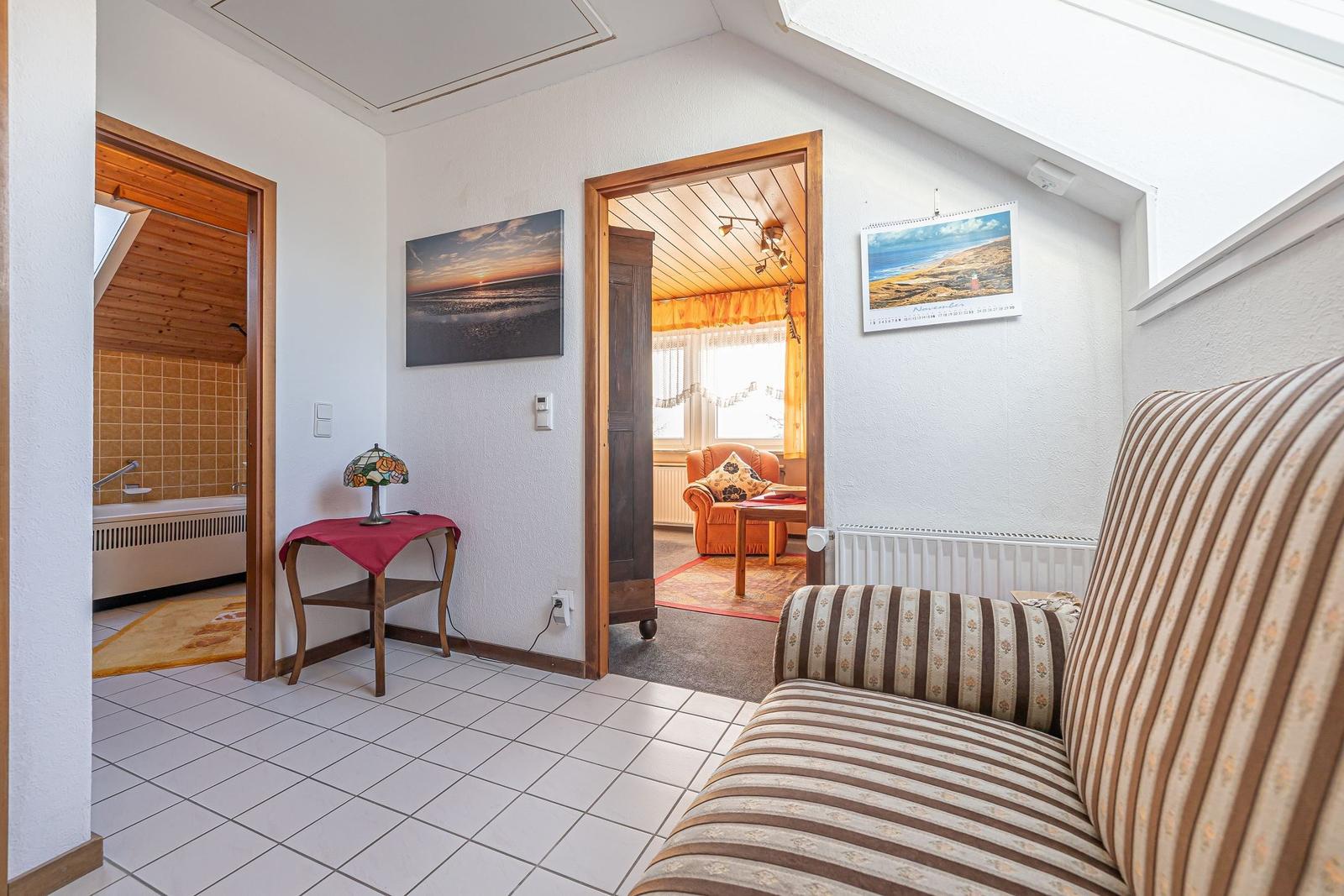 Wohnbereich mit Sofa, Bad und Schlafzimmer. Wandbild und Kalender an der Wand.