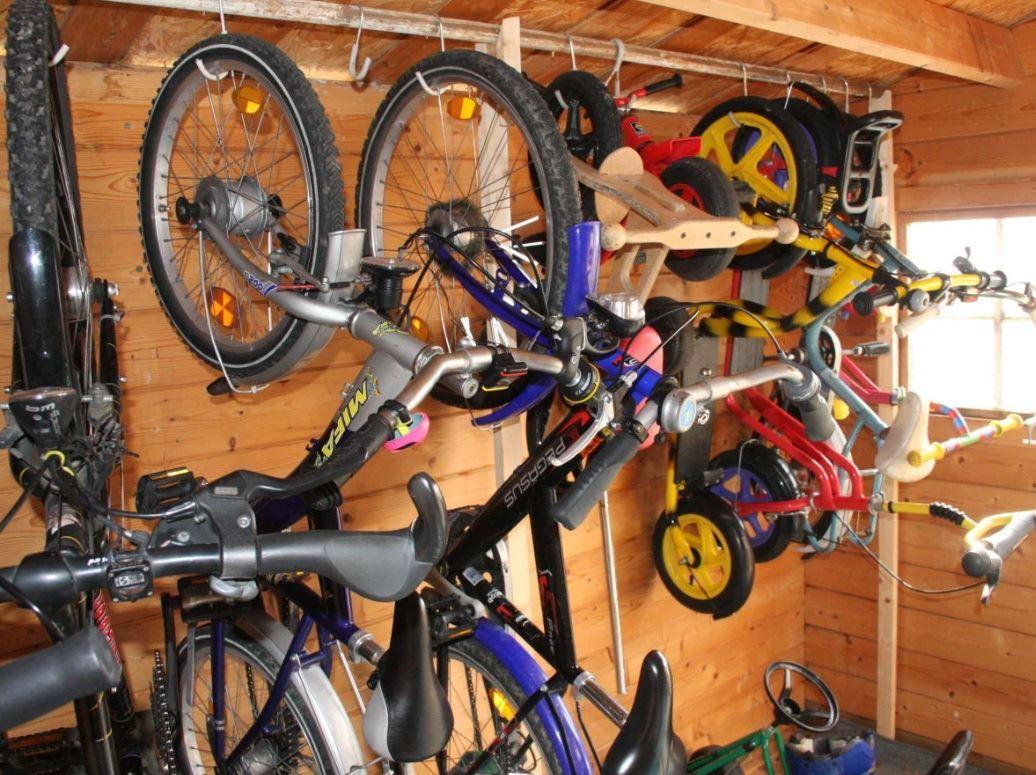 Viele Fahrräder und Kinderfahrräder hängen an Wänden in einem Holzraum.