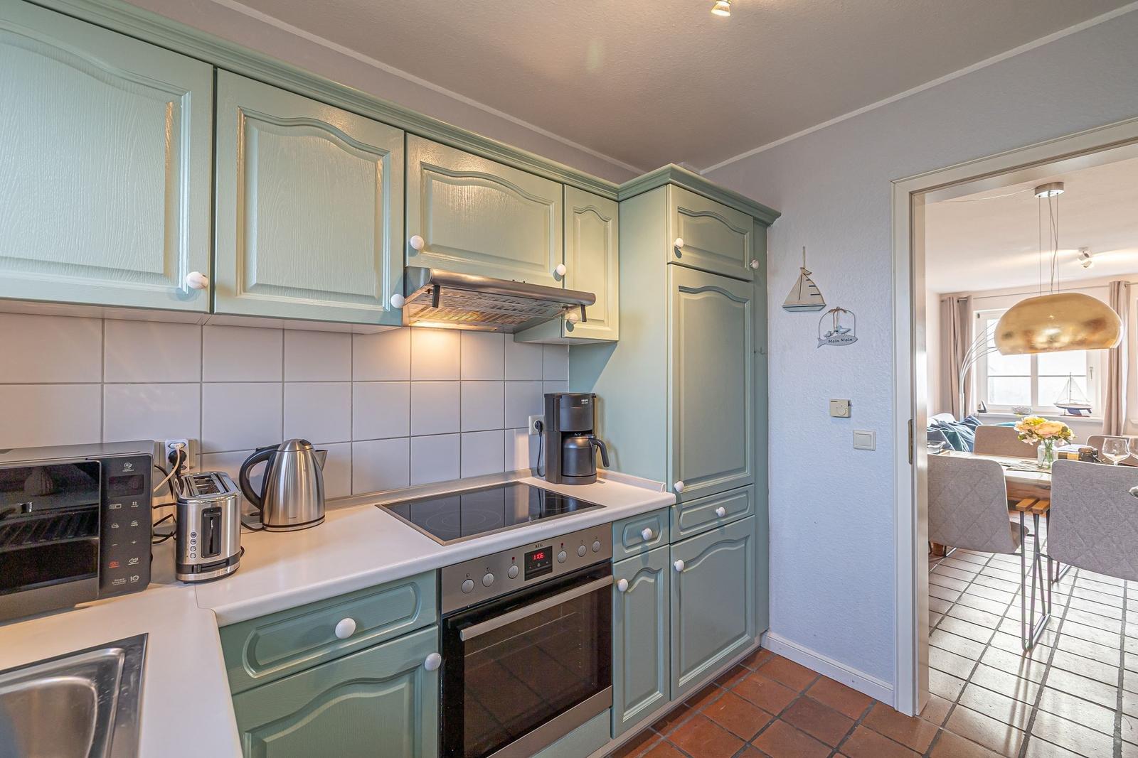 Küche mit hellblauen Schränken, Edelstahlgeräten und Blick in das Esszimmer.