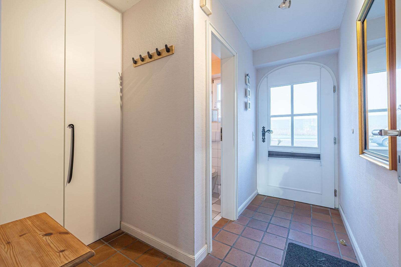 Eingangsbereich mit Garderobe, Haken und Blick in die Toilette.