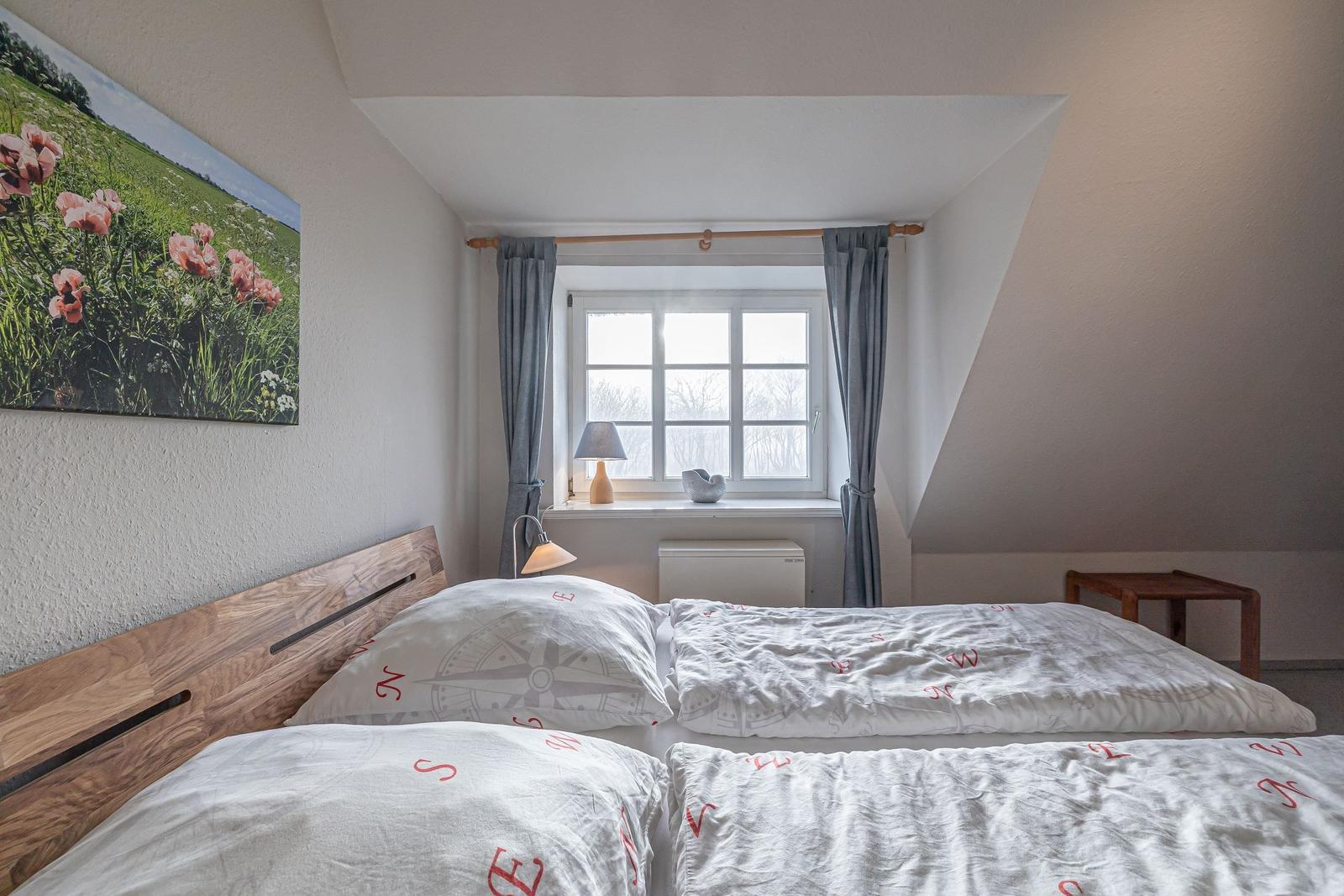 Schlafzimmer mit Doppelbett, Fenster und Wandbild.