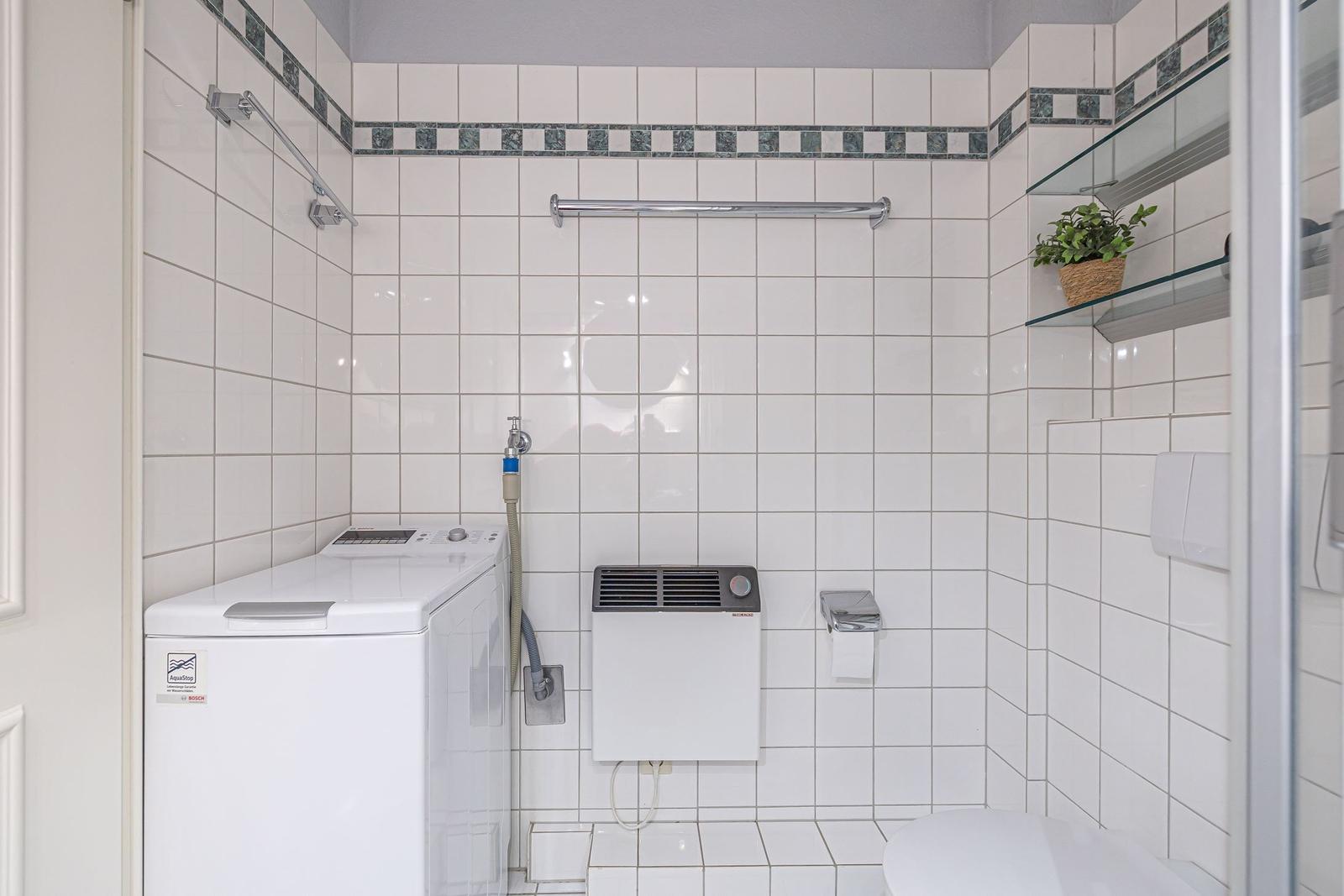 Badezimmer mit Waschmaschine, Toilette und Dusche