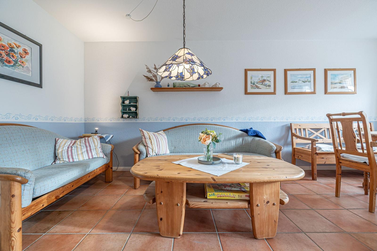 Wohnzimmer mit Holzmöbeln, Tisch und Sofa. Wanddekoration und Deckenleuchte.