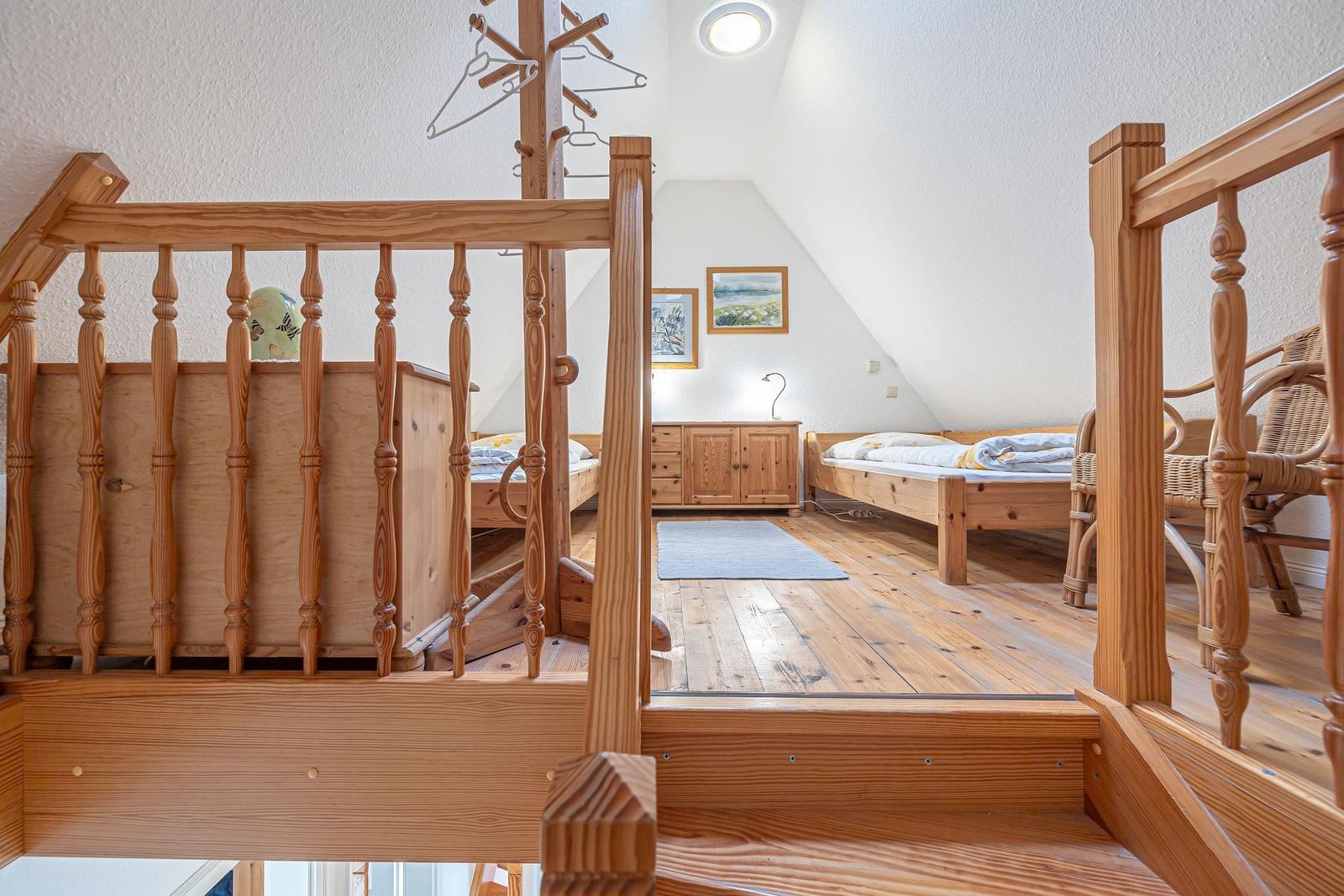 Ein Schlafzimmer mit zwei Betten, Holzboden und einem Kleiderständer.
