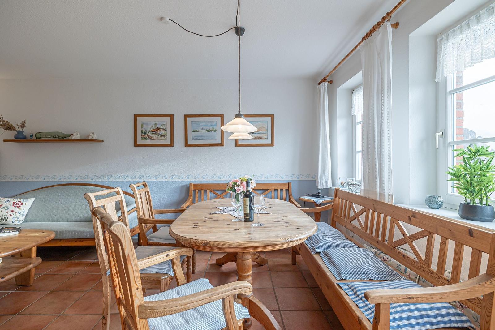 Esszimmer mit Holztisch, Stühlen und Fensterbank. An der Wand hängen zwei Bilder.