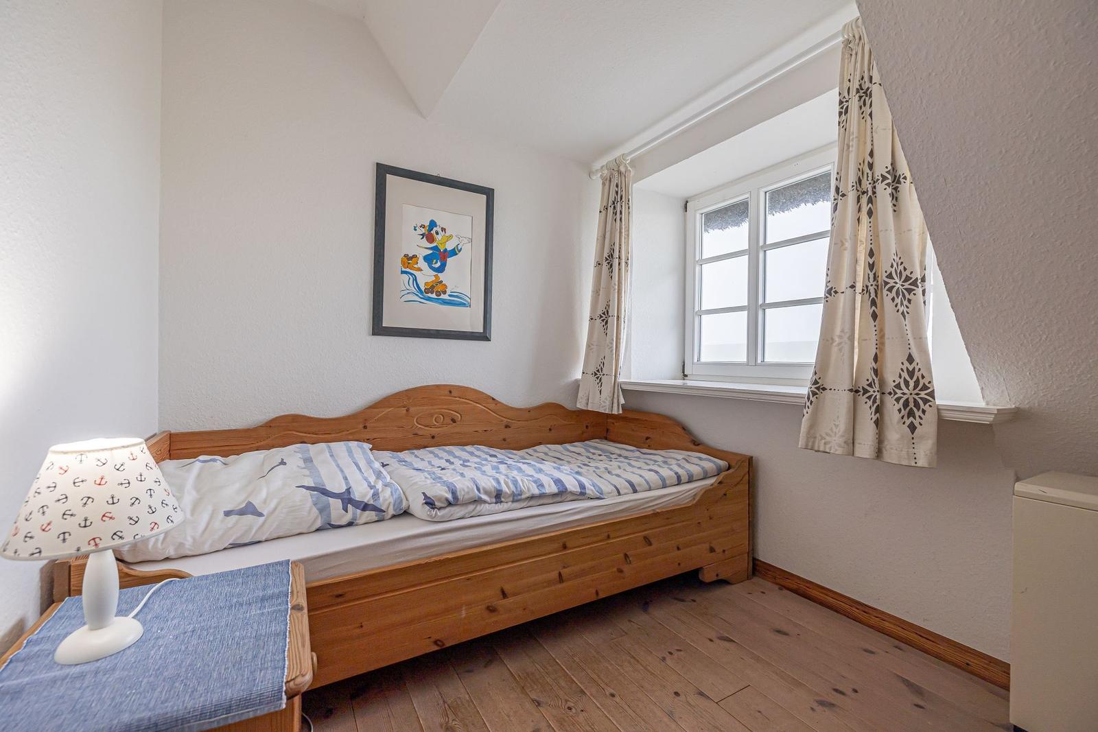 Ein Schlafzimmer mit Holzbett, Fenster und Wandbild.