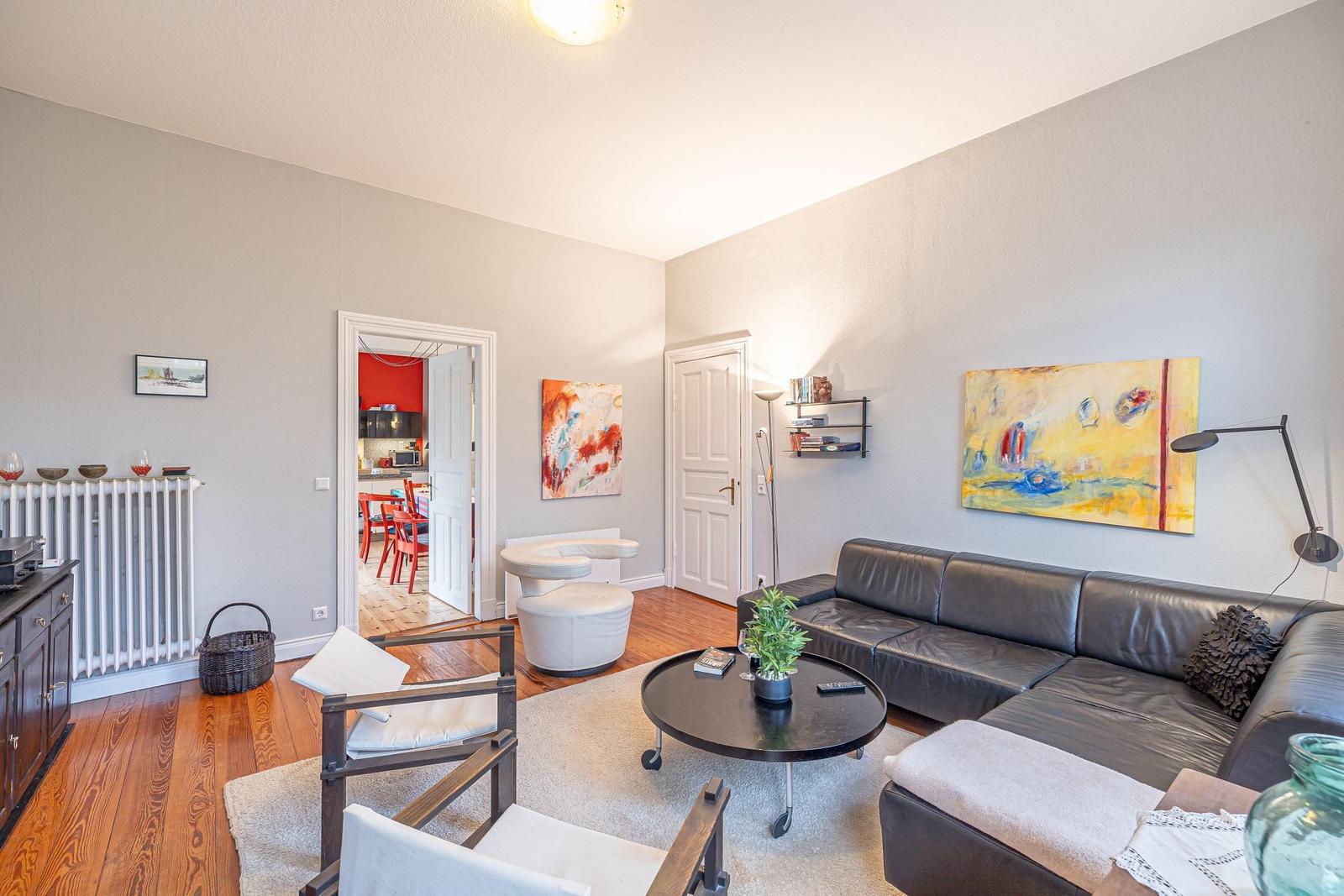 Wohnzimmer mit Ledersofa, Runden Tisch und Kunst an den Wänden.