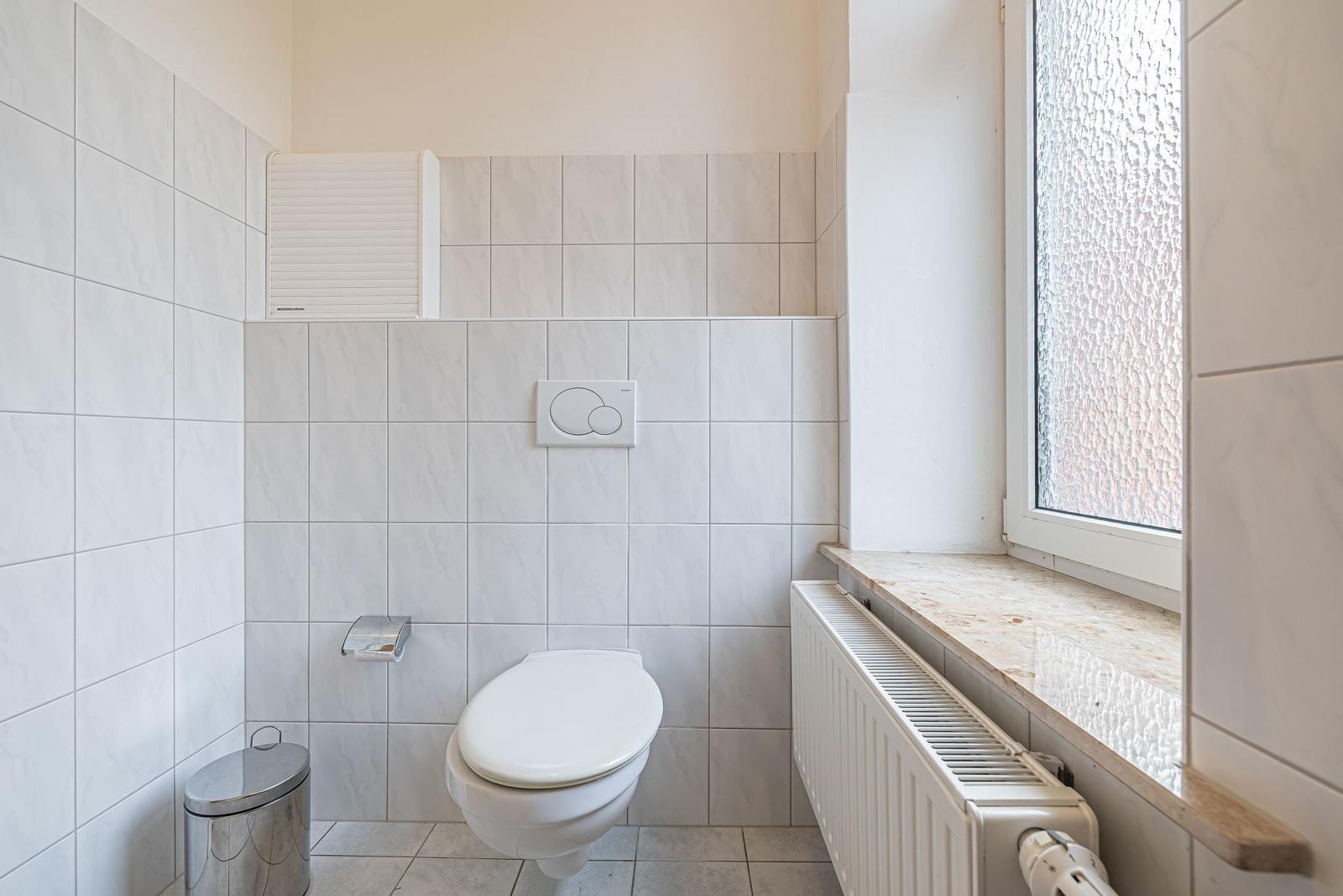 Badezimmer mit Toilette, Fenster und Heizkörper