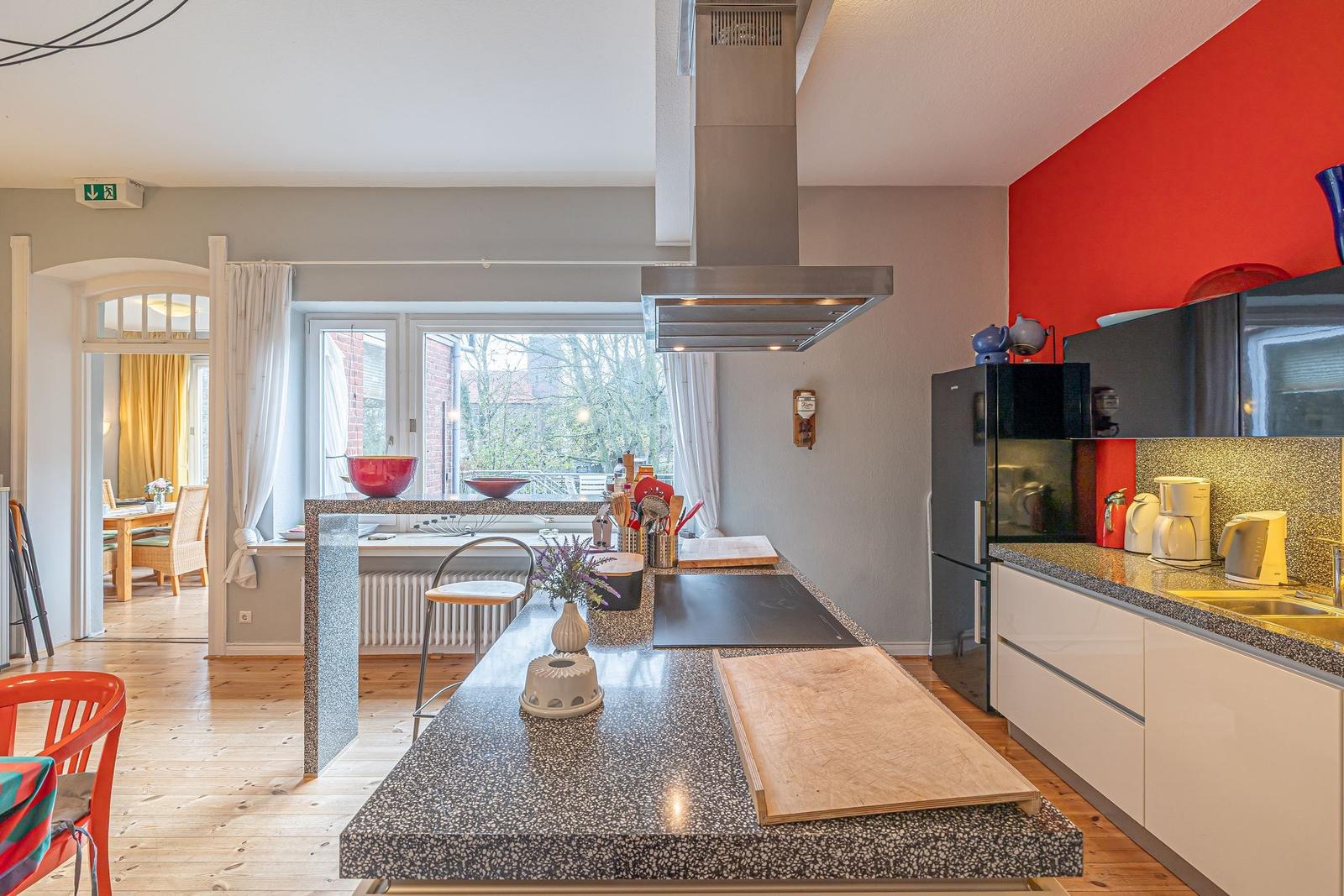 Küche mit Insel, roter Wand und Blick in Esszimmer.
