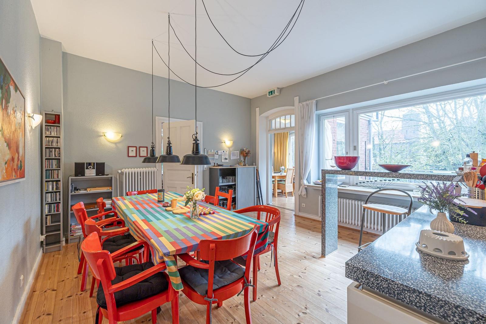 Esszimmer mit farbigem Tisch, roten Stühlen und Kücheninsel mit Arbeitsplatte.