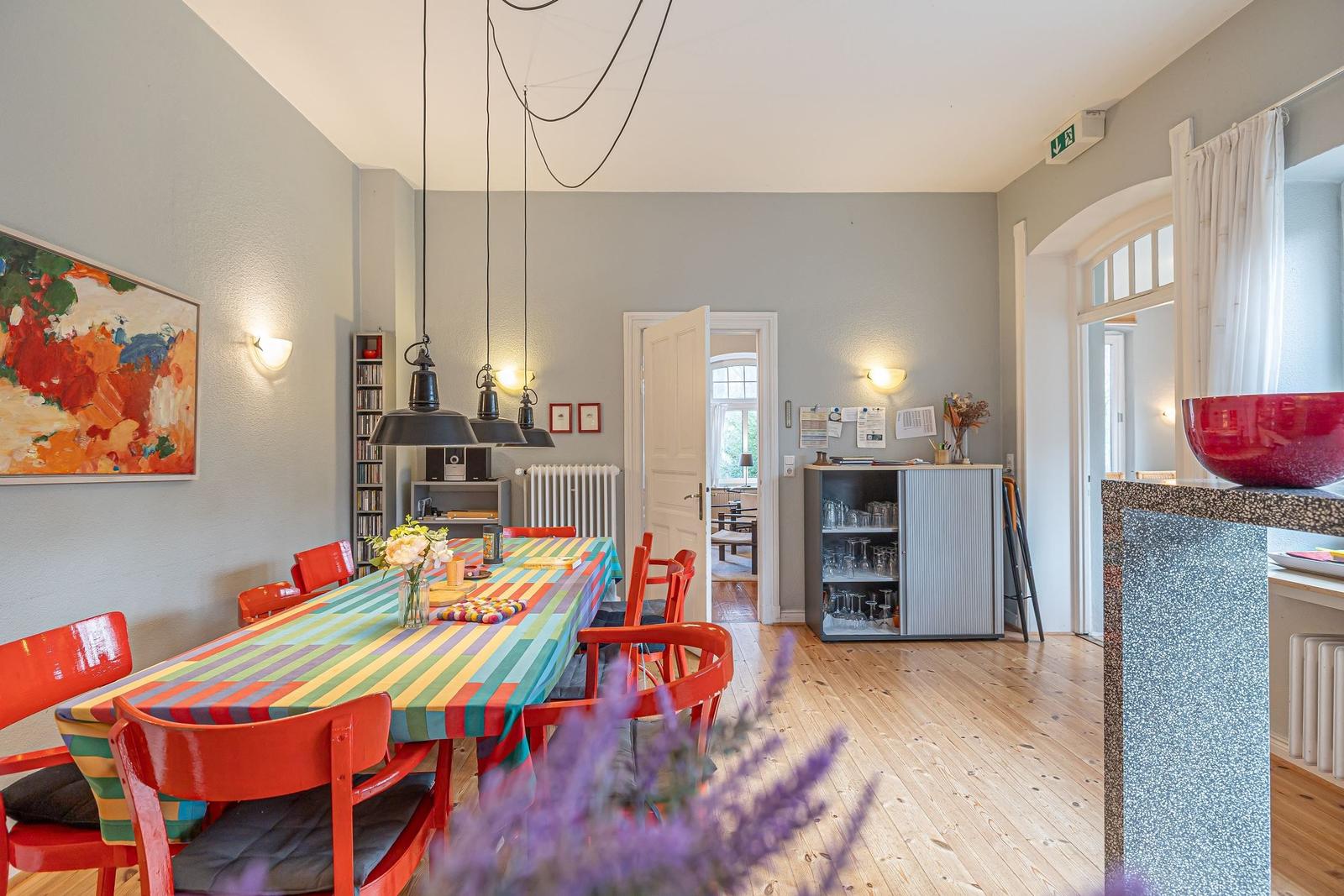 Esszimmer mit Tisch, Stühlen und Wandbild. Holzboden und Licht.