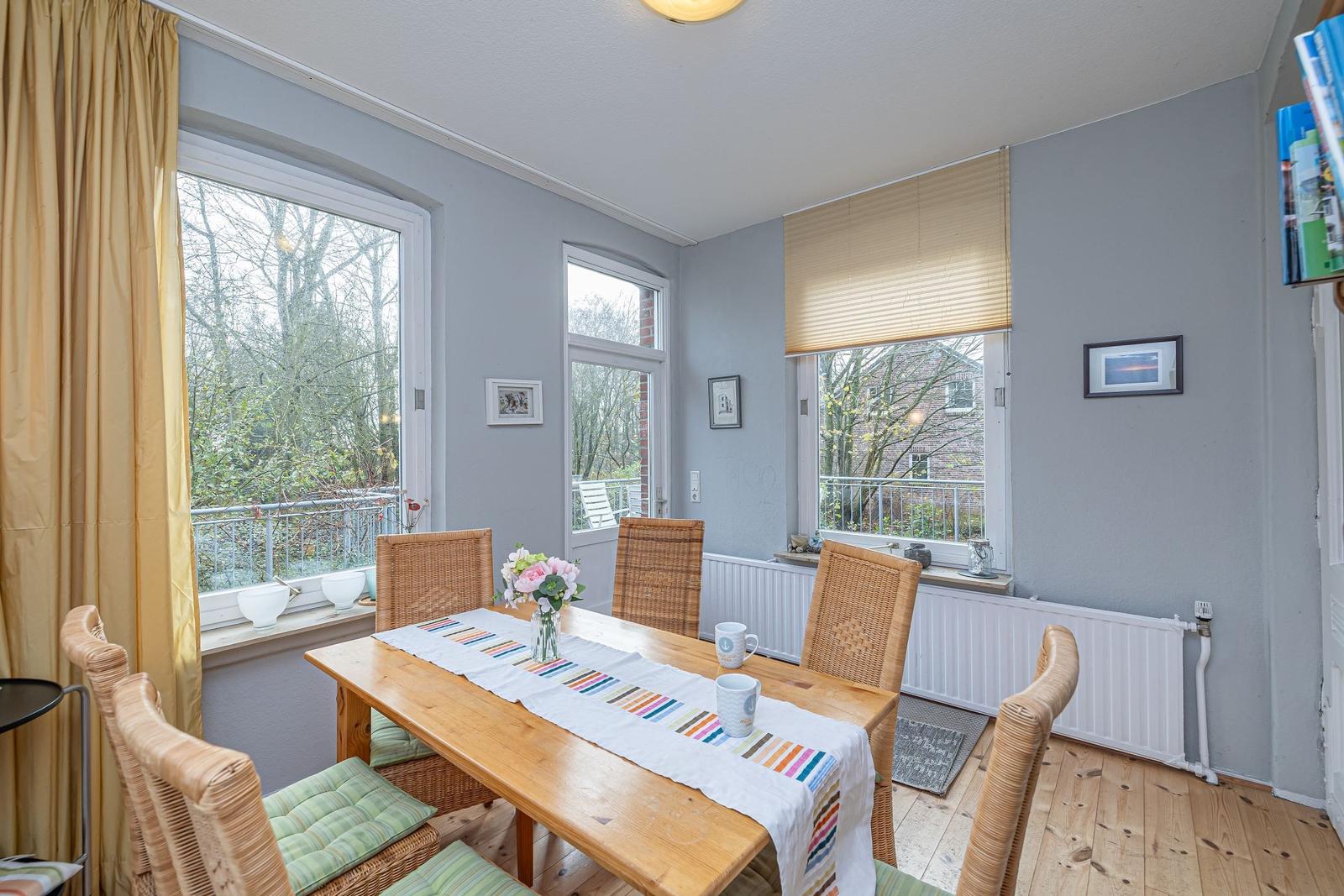 Esszimmer mit Holztisch, Stühlen und Fenstern zur Terrasse