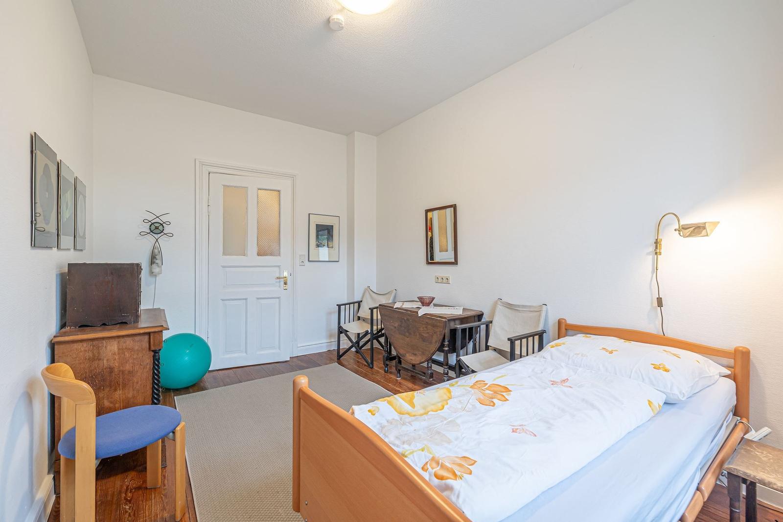 Ein Schlafzimmer mit Bett, Tisch, Stühlen und einer Tür.