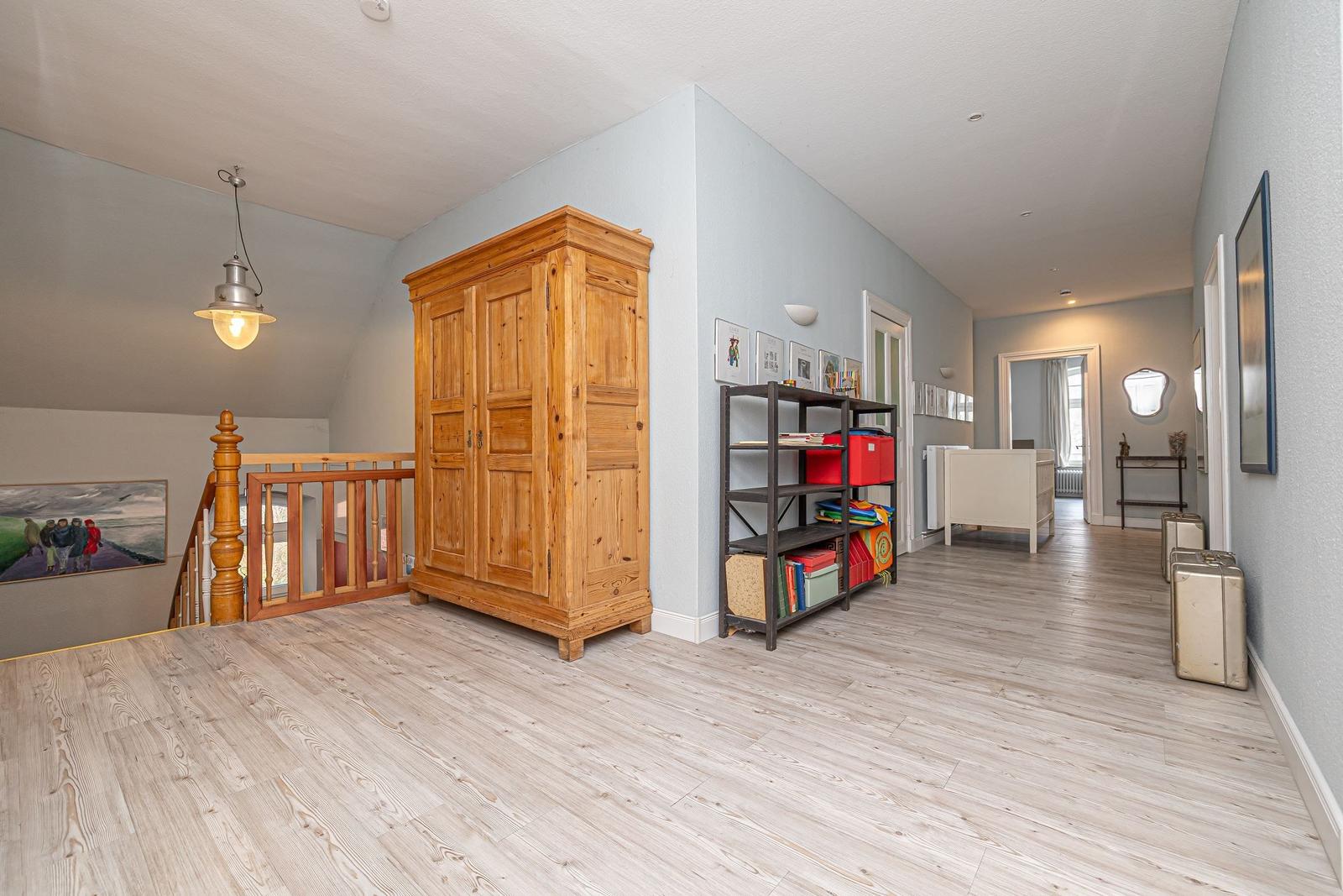 Hallenraum mit Holzschrank, Regal und Koffer. Holzboden und Wandfarbe.