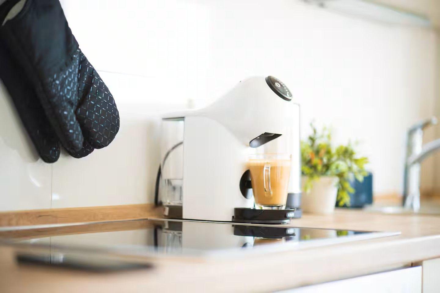 Eine Kaffeemaschine gießt Kaffee in ein Glas auf der Arbeitsfläche.