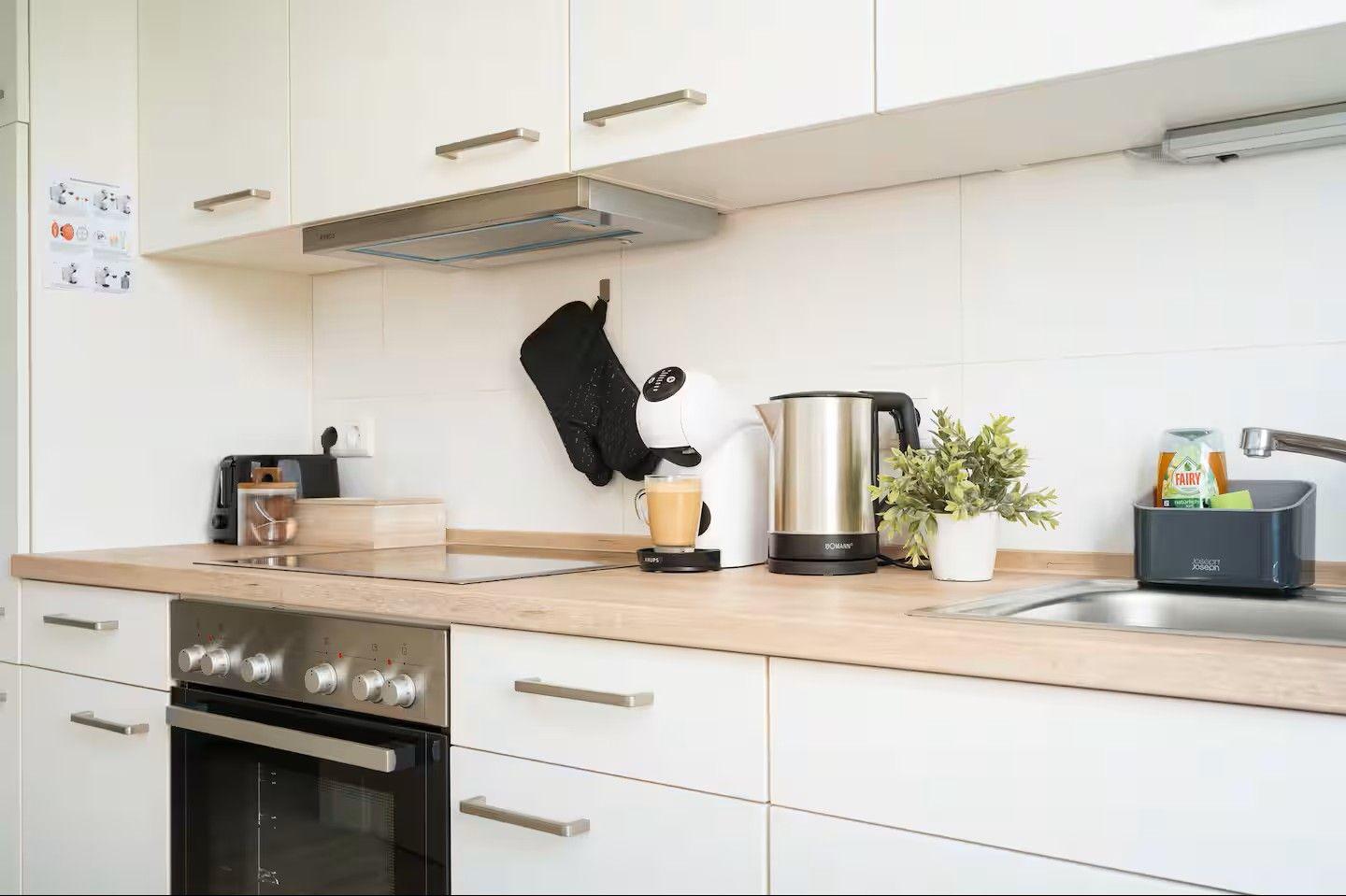 Küche mit Arbeitsplatte, Spüle, Herd und Kaffeemaschine.