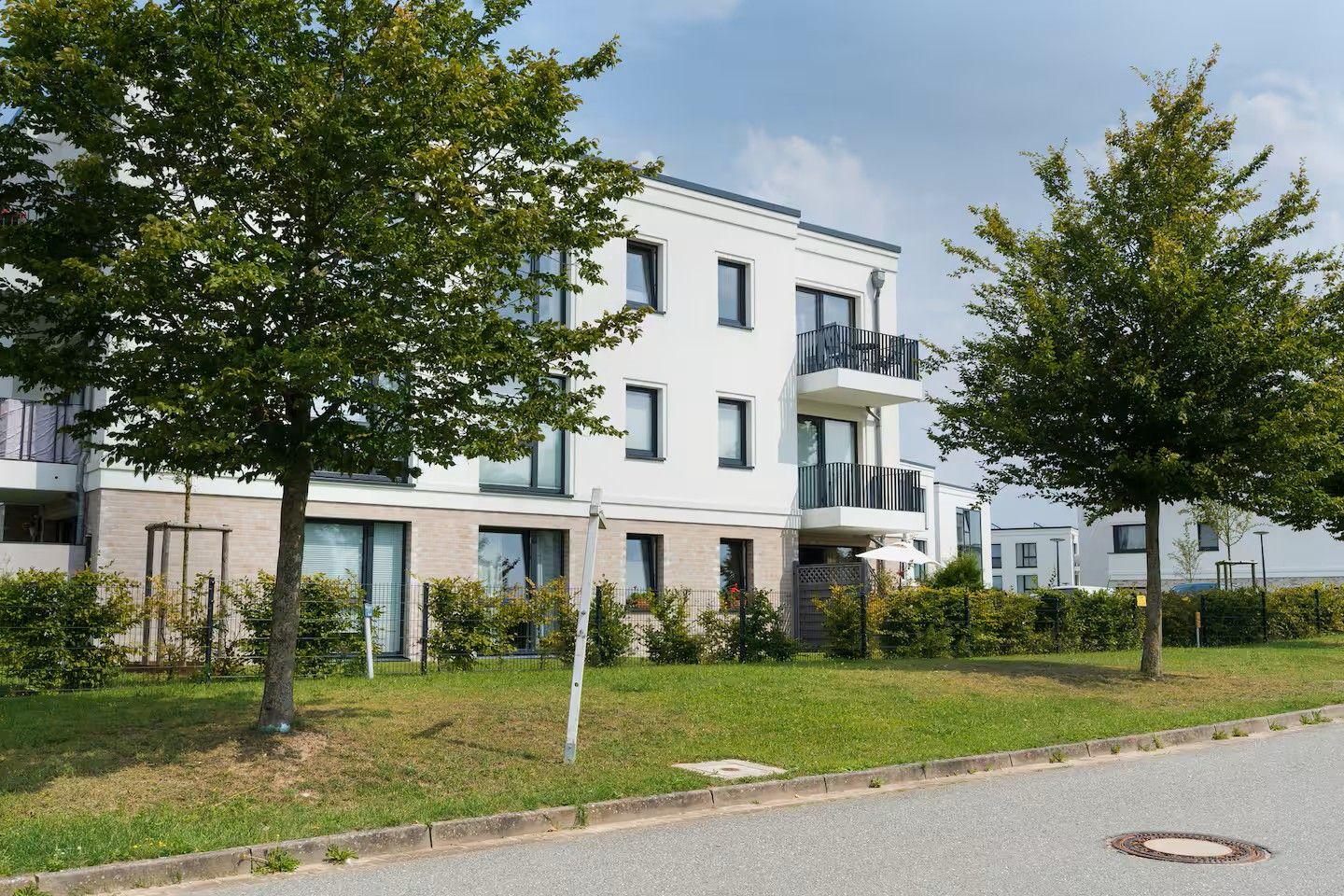 Moderne Wohnung mit Balkon, begrünter Außenbereich und Bäumen