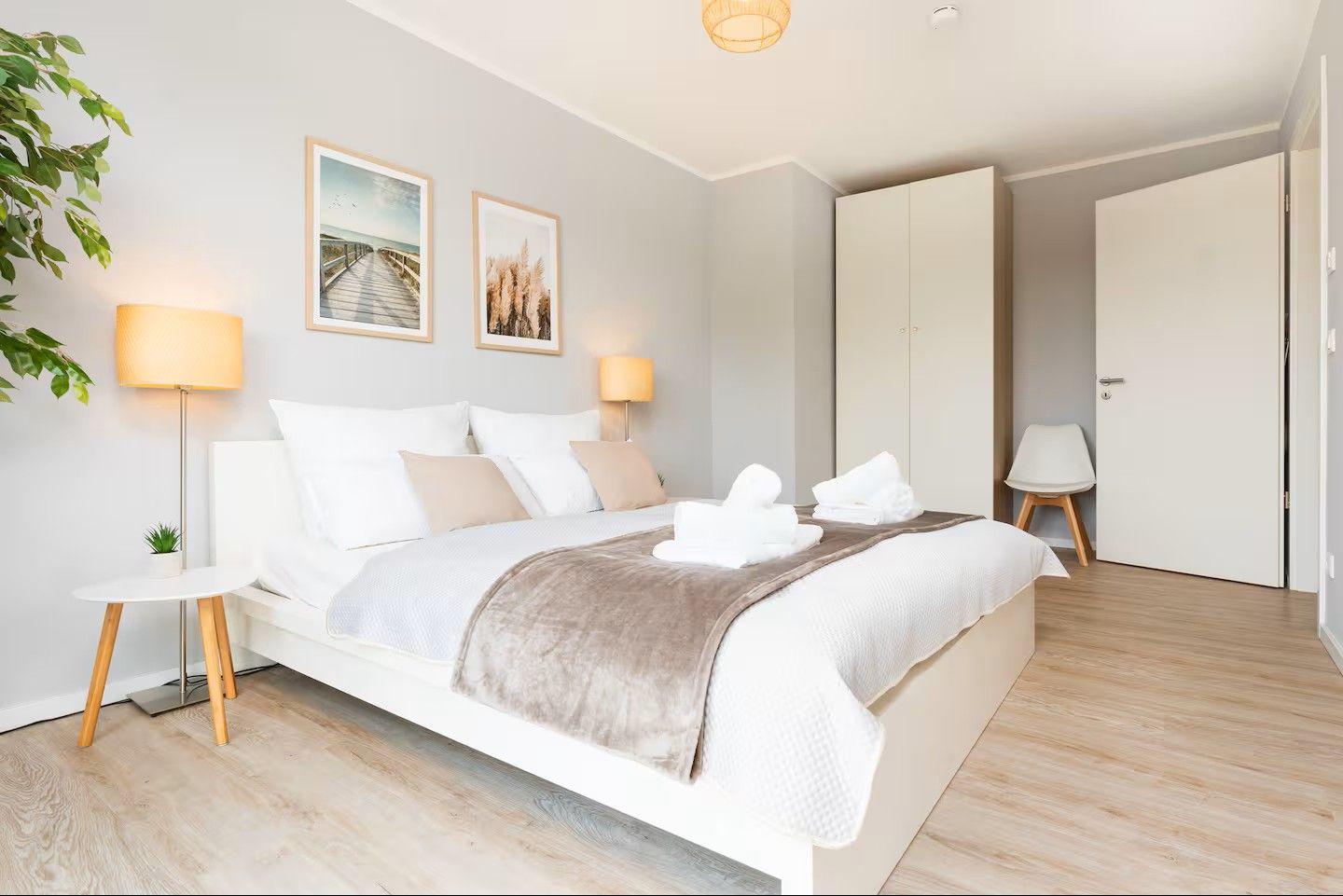 Ein Schlafzimmer mit Bett, Nachttisch, Lampen und Bildern an der Wand.