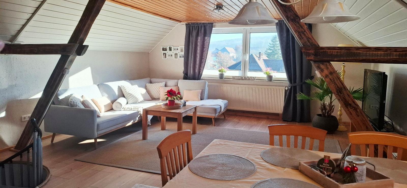 Wohn- und Essbereich mit Sofa, Tisch und Fensterblick.