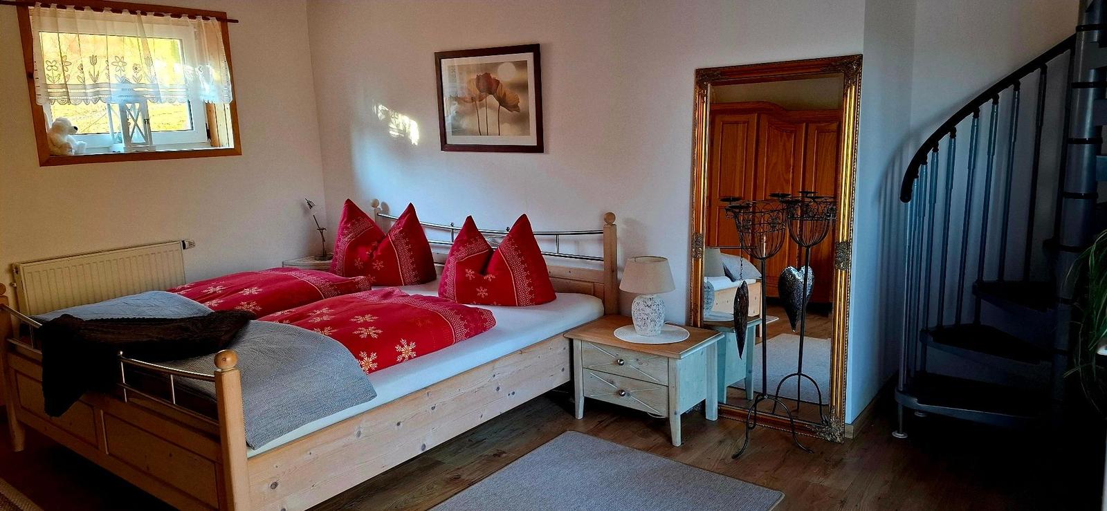 Schlafzimmer mit Doppelbett, Fenster, Spiegel und Treppe