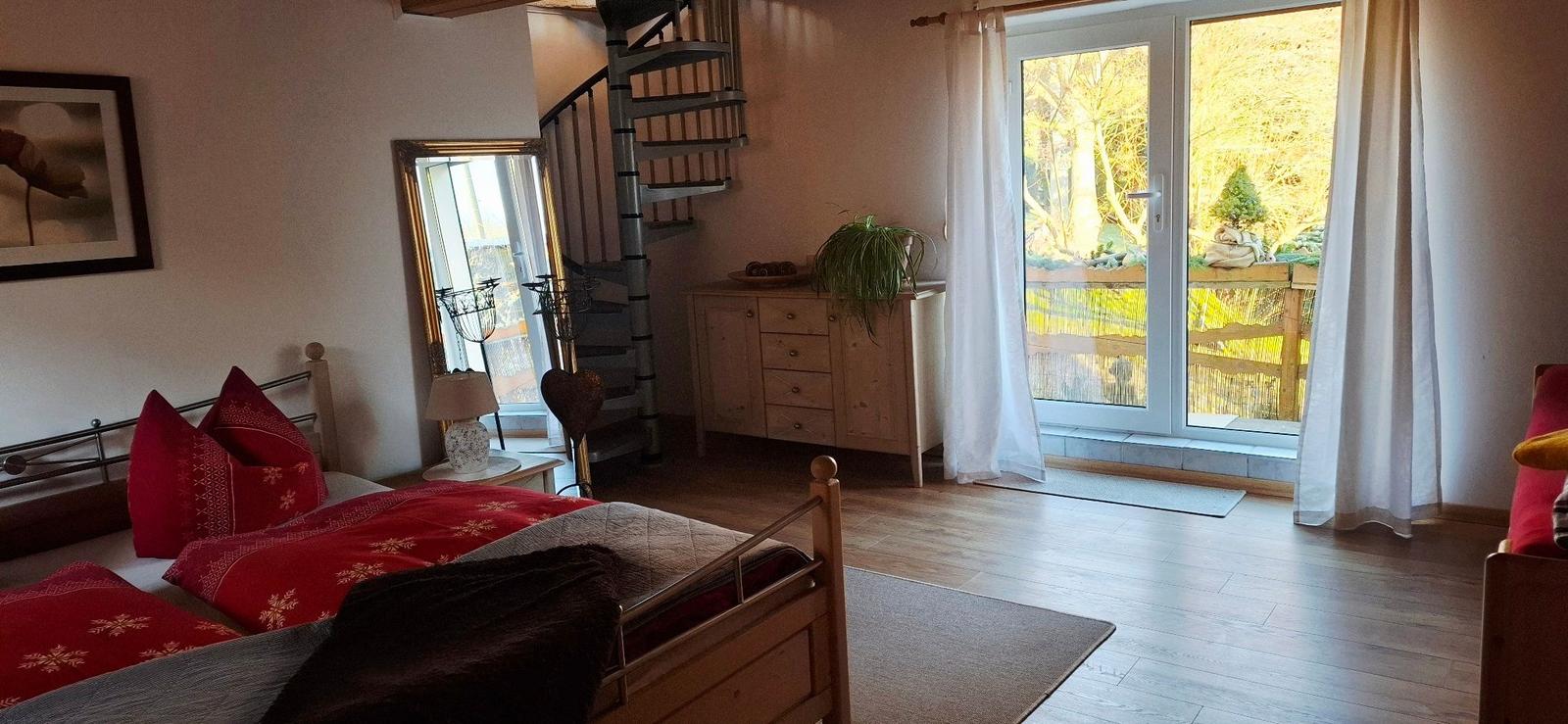 Schlafzimmer mit Bett, Schrank und Glasfront zur Terrasse