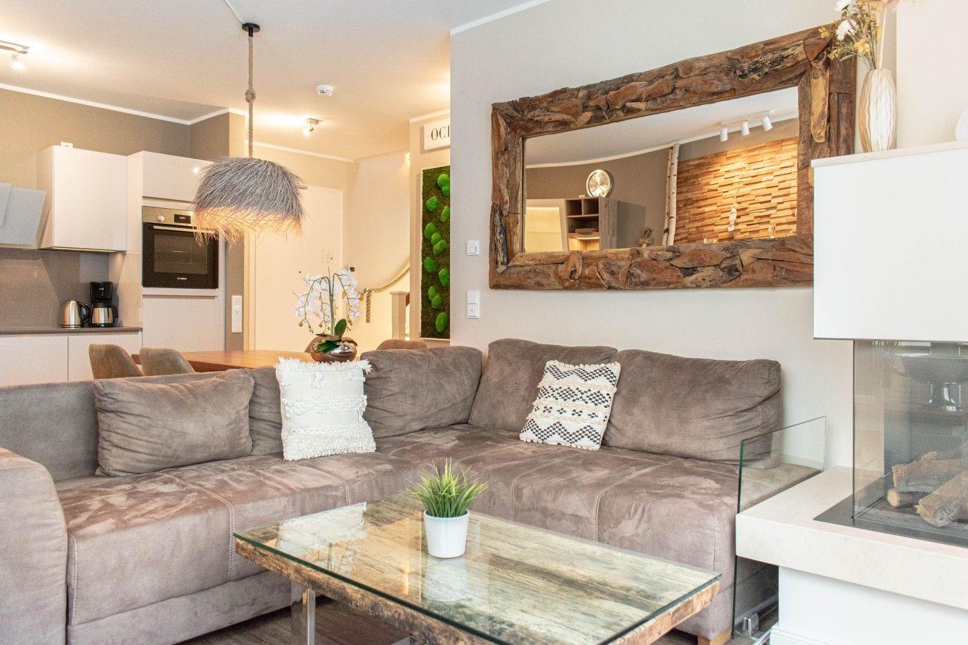 Wohnzimmer mit Sofa, Couchtisch und Kamin. Großer Spiegel an der Wand.