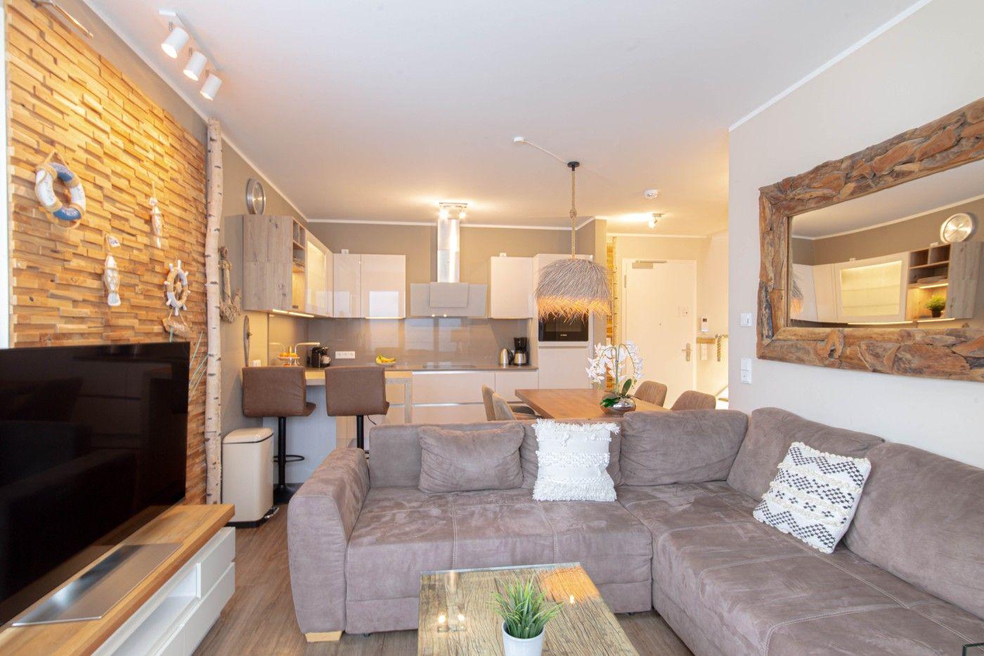 Wohnzimmer mit Sofa, Couchtisch und Küchenbereich im Hintergrund.