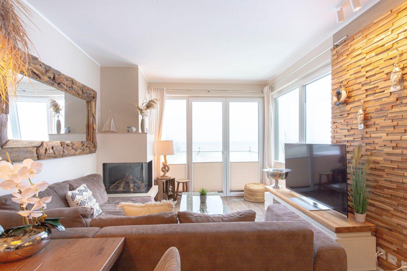 Wohnzimmer mit Sofa, Kamin und TV an Holzwand