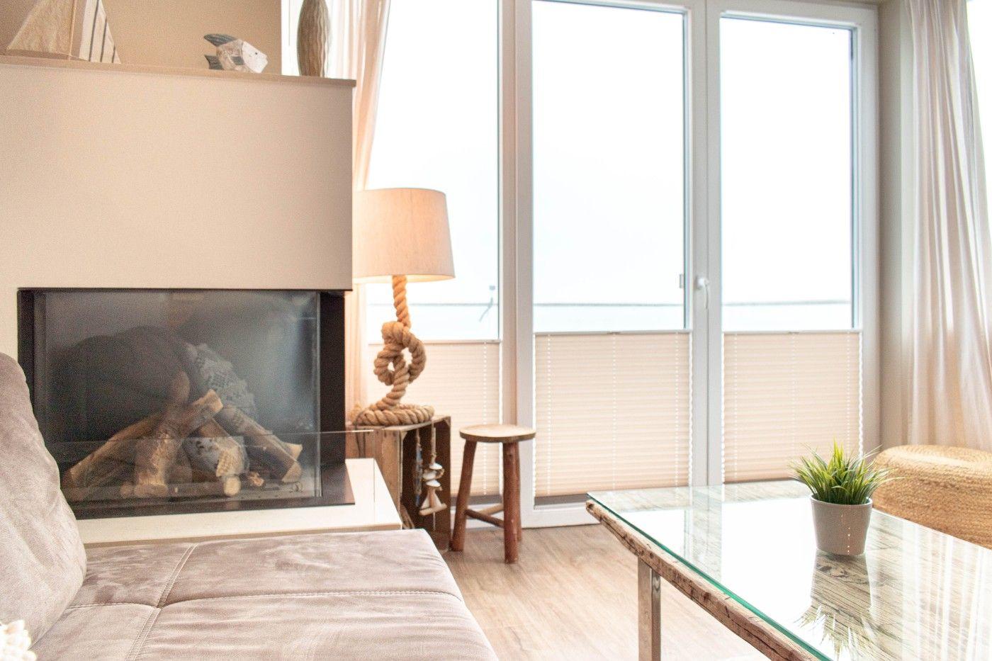 Wohnzimmer mit Kamin, Glas-Tisch und Fenster zur Aussicht.