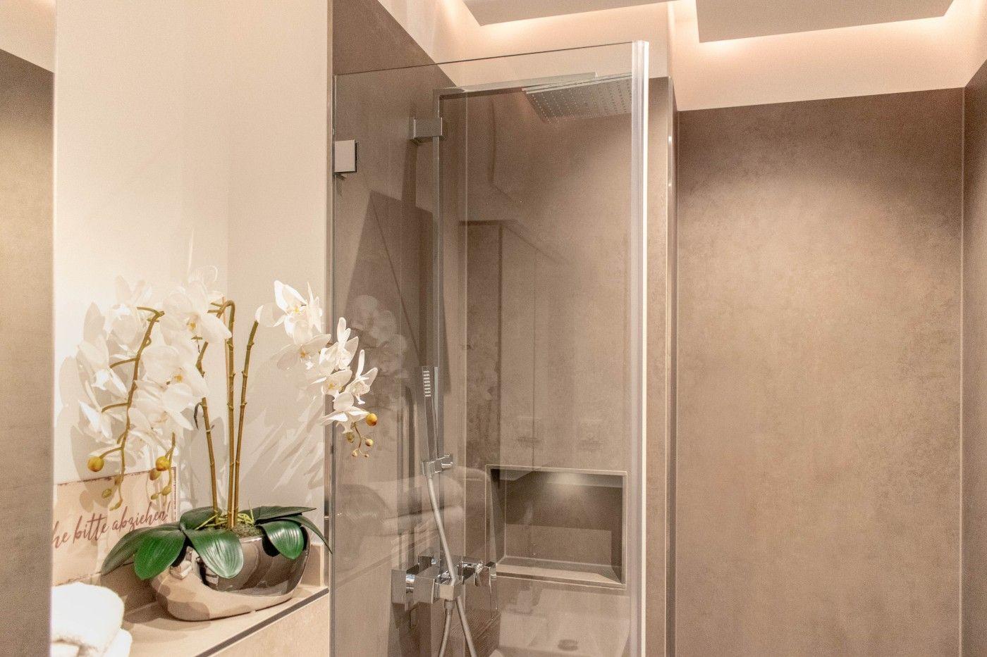 Dusche mit Glaswand und Orchidee auf Ablagefläche