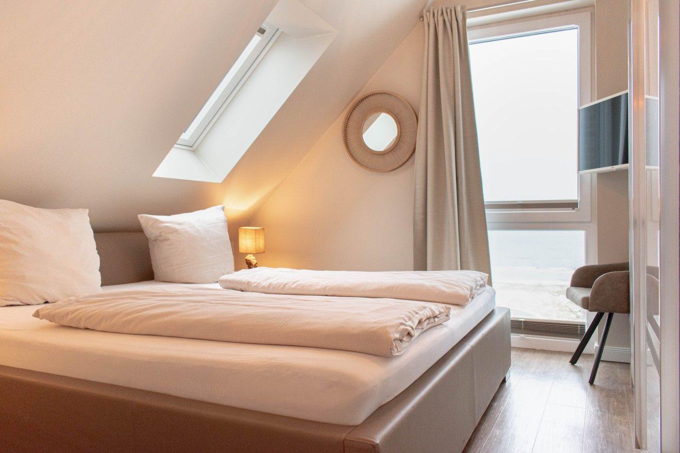 Schlafzimmer mit Dachschrägen, Dachfenster und Blick aufs Meer.