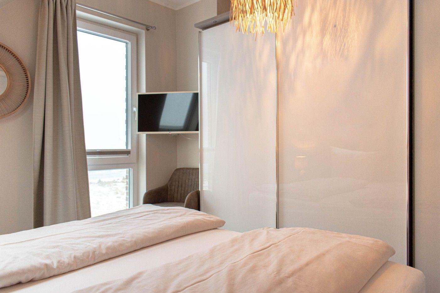 Schlafzimmer mit Bett, Fenster, TV und Schwebetüren