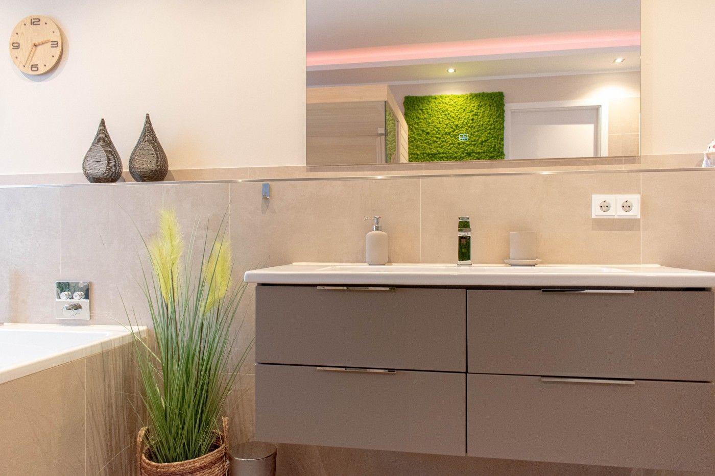 Badezimmer mit Waschbecken, Spiegel und Pflanze.