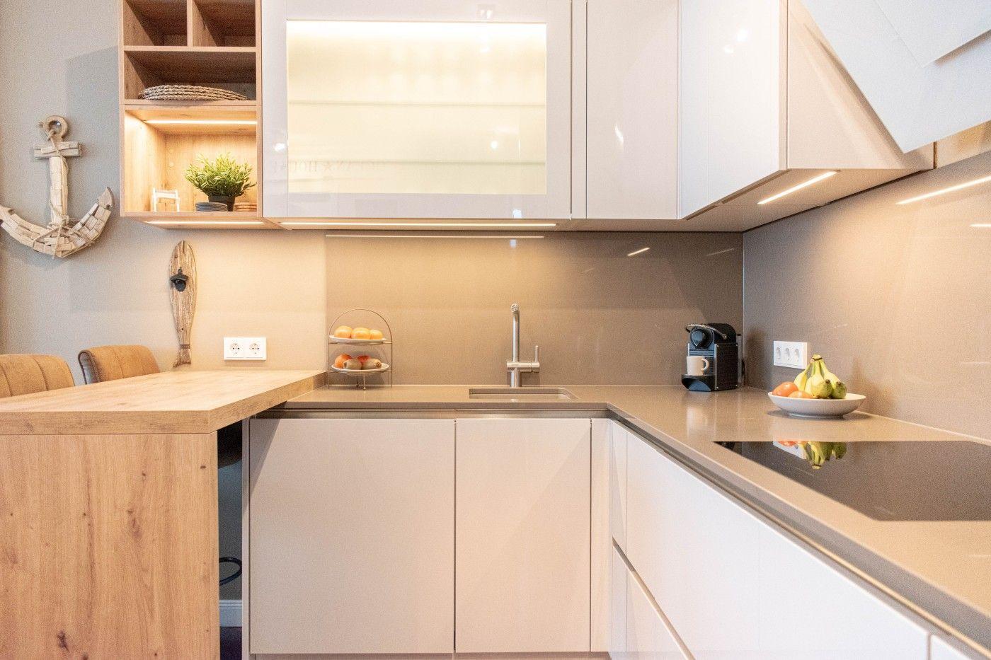 Küche mit Holzinsel, weißen Schränken und Küchenzeile mit Spüle und Kochfeld.